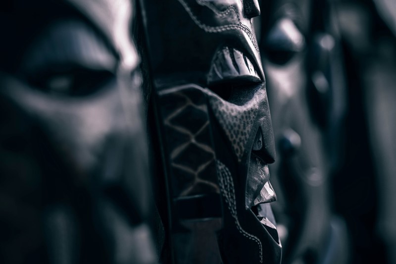 a dim close up of wooden tribal masks, african statues 4k