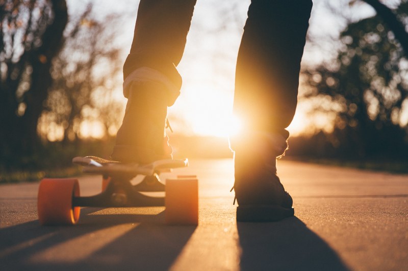the silhouette of a person riding a skateboard with orange wheels at sunset at university of northern iowa, northern iowa skateboarder 4k