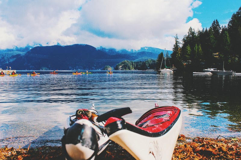 two kayaks on the shore and several more on the choppy surface of a lake, kayaks on a lake 4k