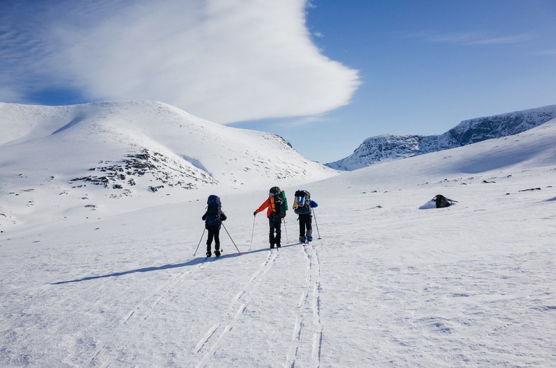 group of hikers going up a snowy mountain with walking sticks and backpacks in kolsky district, hiking up kolsky district 4k