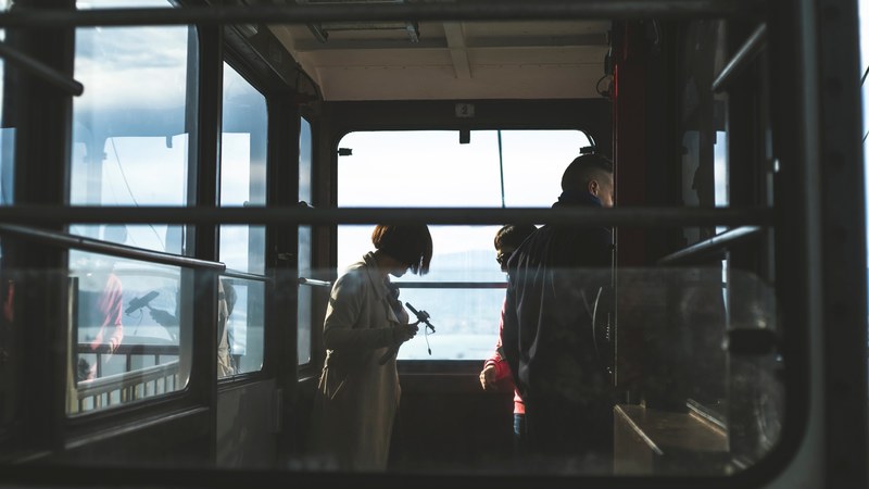 several commuters in shadow stand aside a railing on a train, commuters on a train 4k