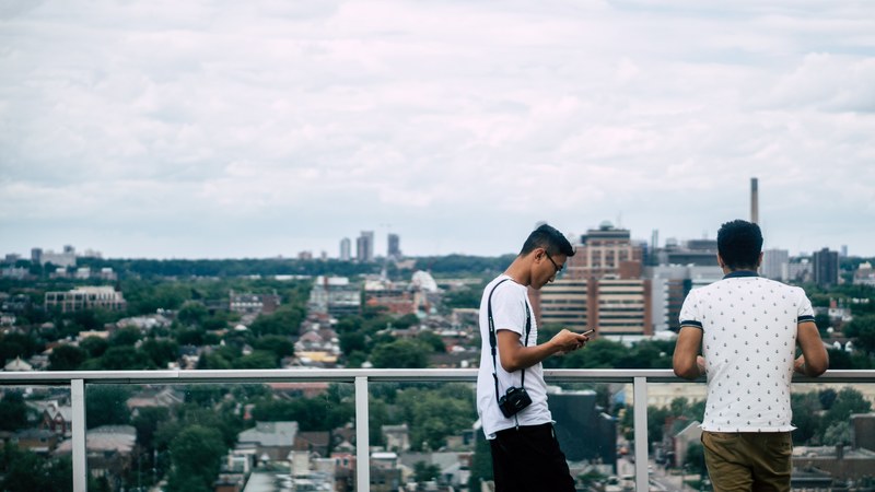 two men are on a balcony overlooking the toronto cityscape, _men by railing in toronto 4k