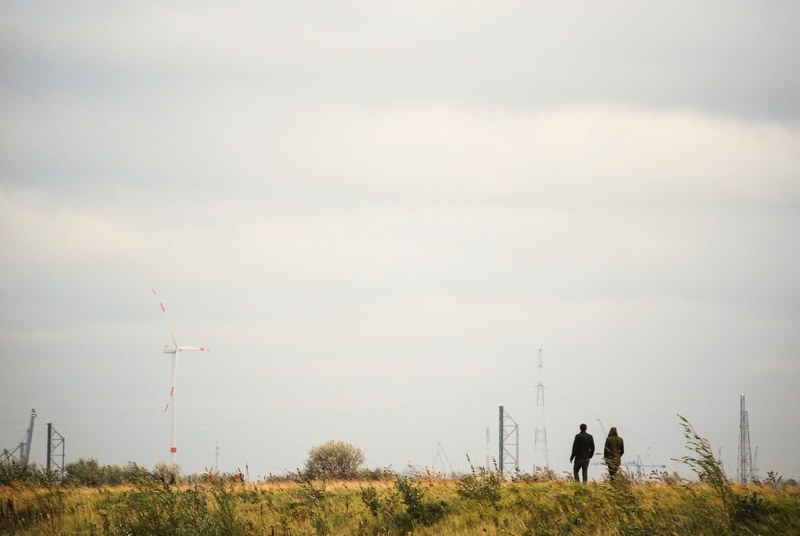couple walks through a rural grassy meadow alone, walking through fields 4k