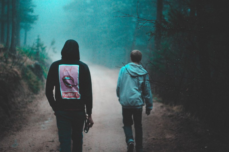 young friends in graphic hoodies walk through foggy woods, lost in the wilderness 4k