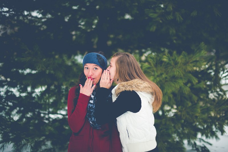 two young friends whispering secrets to each other in winter, telling secrets 4k