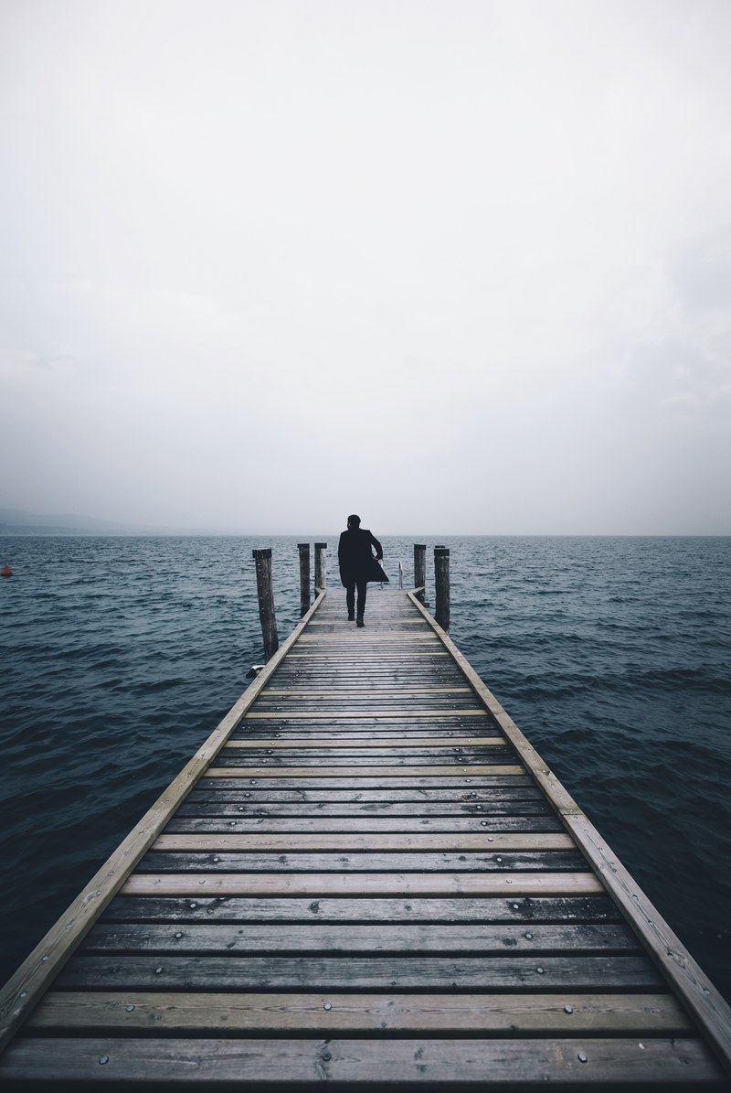 person walks on pier on a misty morning near the ocean, walking towards the water 4k