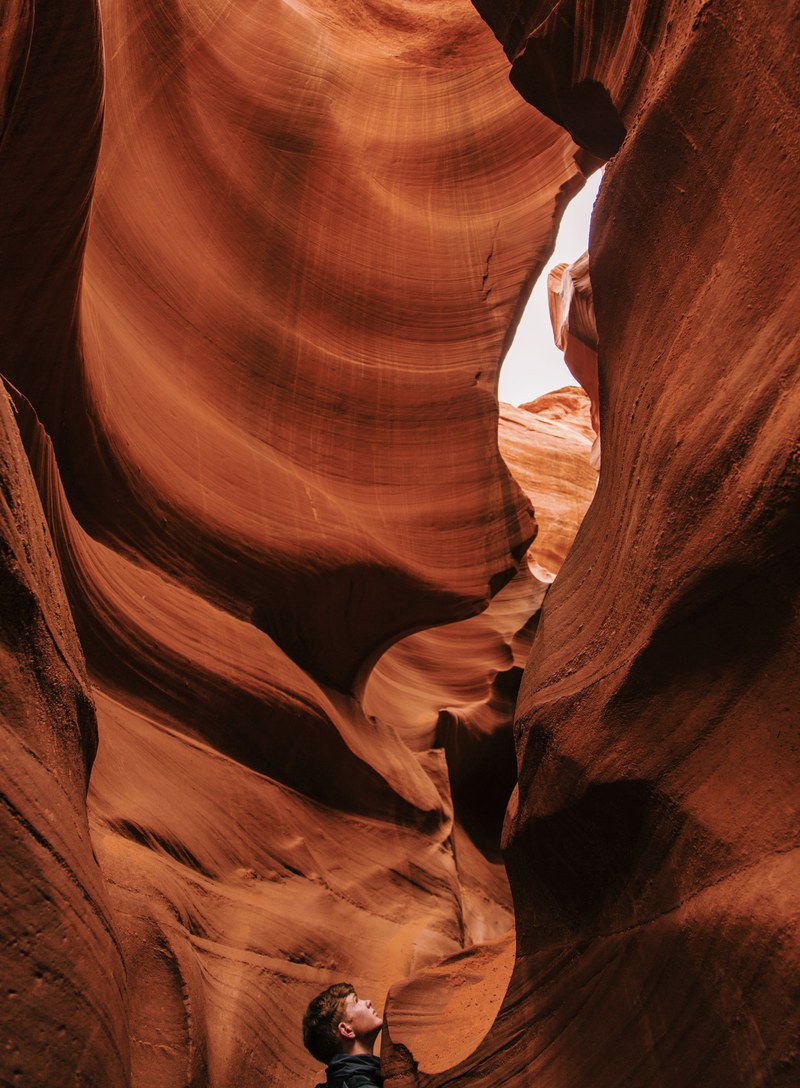 a man looking up the swirling red sandstone walls of a canyon, lost in wonder 4k