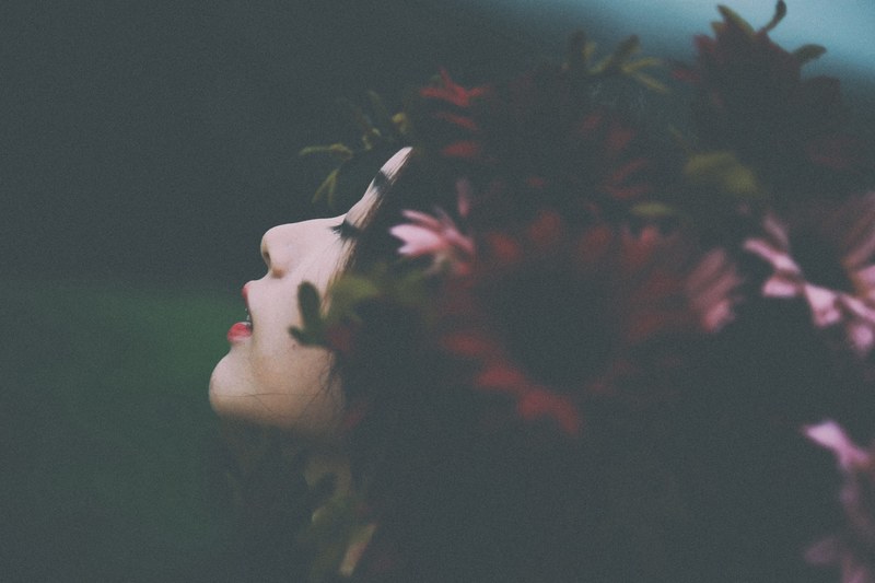 young asian woman with flowers in her dark hair with face uplifted and eyes closed expectantly, with flowers in her hair 4k