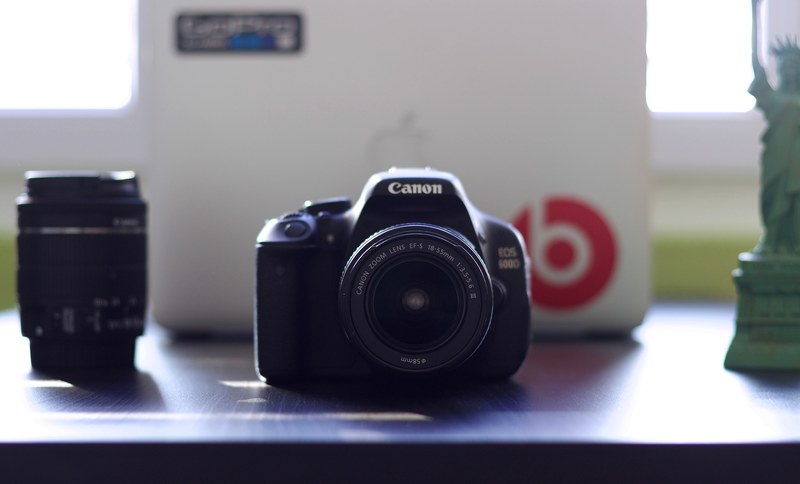 canon eos 600d camera with an 85mm lens next to another lens a miniature statue of liberty figurine and a macbook with a beats sticker, canon camera and lens 4k