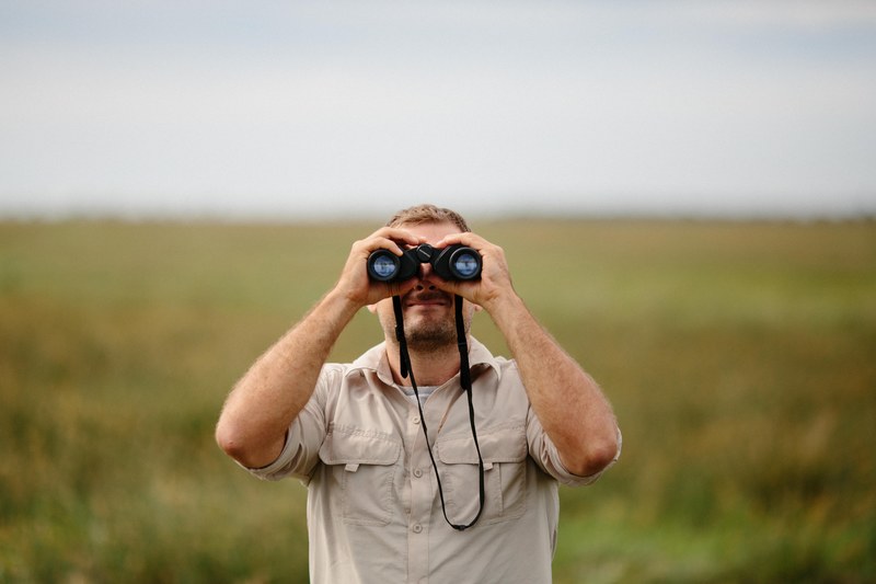 man on a safari expedition looking through binoculars, exploration of africa 4k