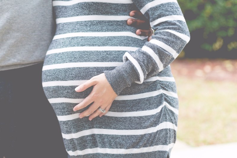 pregnant woman in a striped shit holds stomach as her boyfriend holds her close, any day now 4k