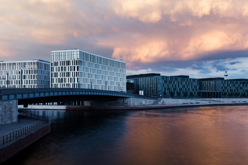 rows of buildings above open water underneath clouds at sunset in berlin germany, modern berlin architecture by river spree 4k