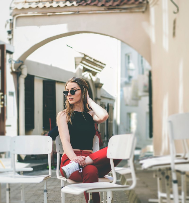 woman in red pants and sunglasses sitting along on cafe chairs, victoria 4k
