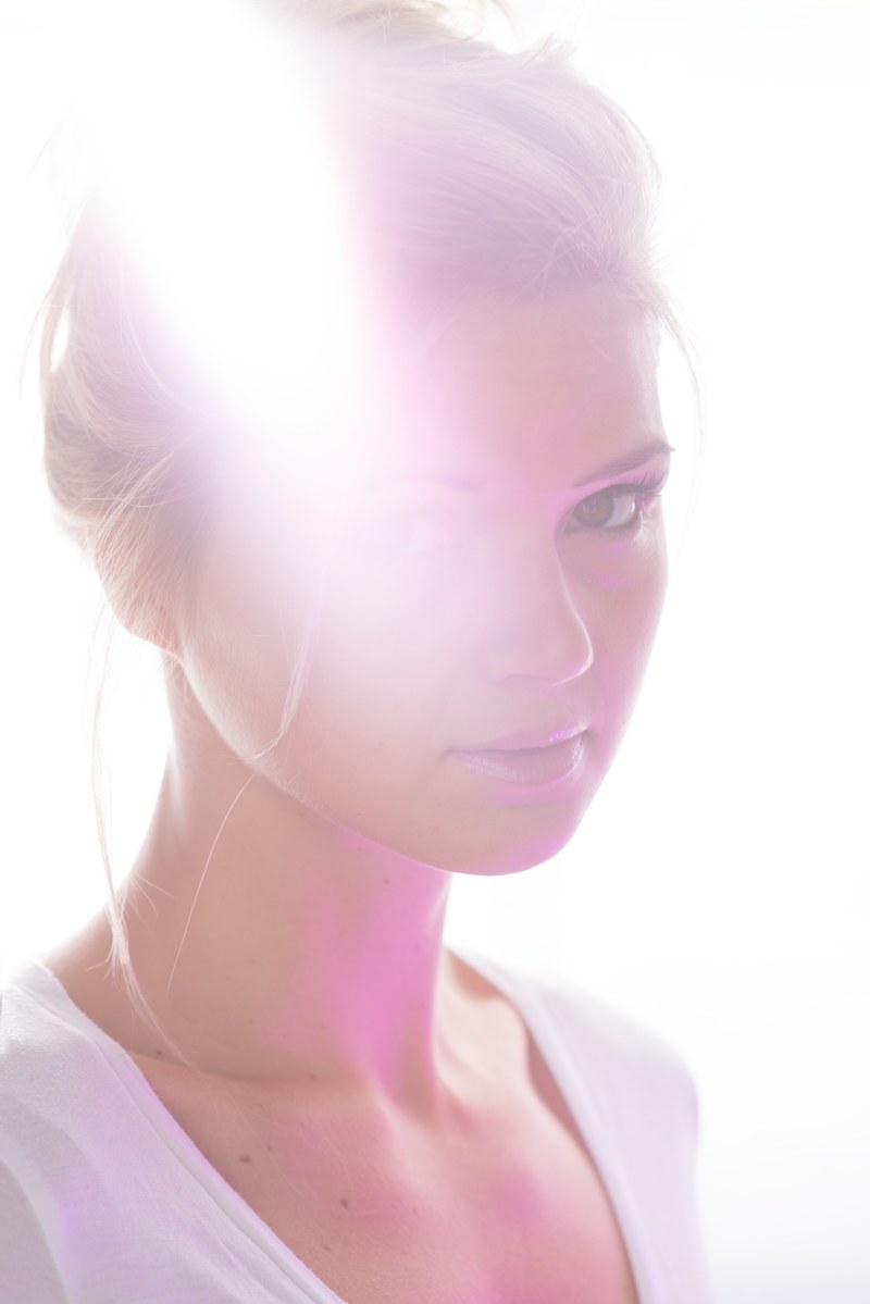 a portrait of a young blonde woman against bright sunrays, sunlit womans portrait 4k