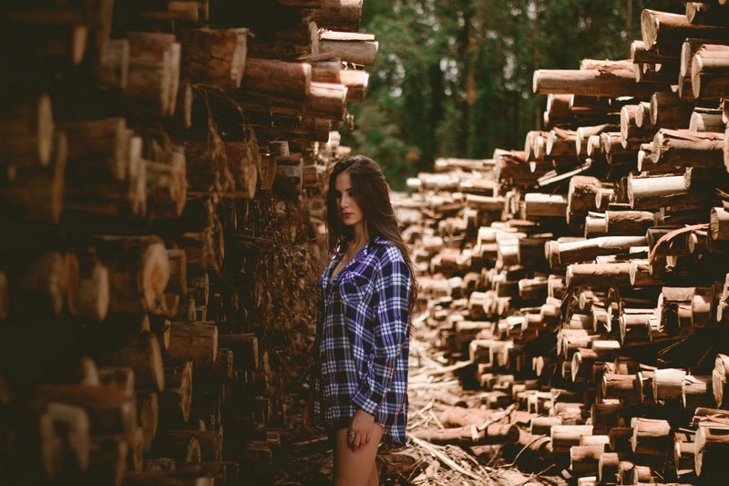 a woman in a plaid shirt stands aside stacks of lumber, woman standing aside lumber 4k