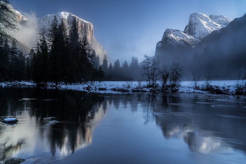 a misty frozen lake with a reflection and view of snow capped mountains in yosemite valley, snowy mountains reflection in a lake 4k