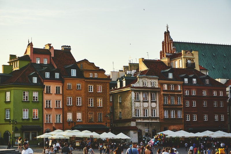 tourists strolling near quaint tenement houses in the castle square in warsaw, tourists at a historic square 4k