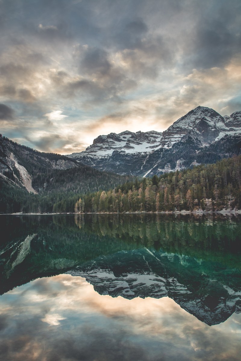 a scenic view of snowy mountains reflected in the surface of lake tovel, mountains by lake tovel 4k
