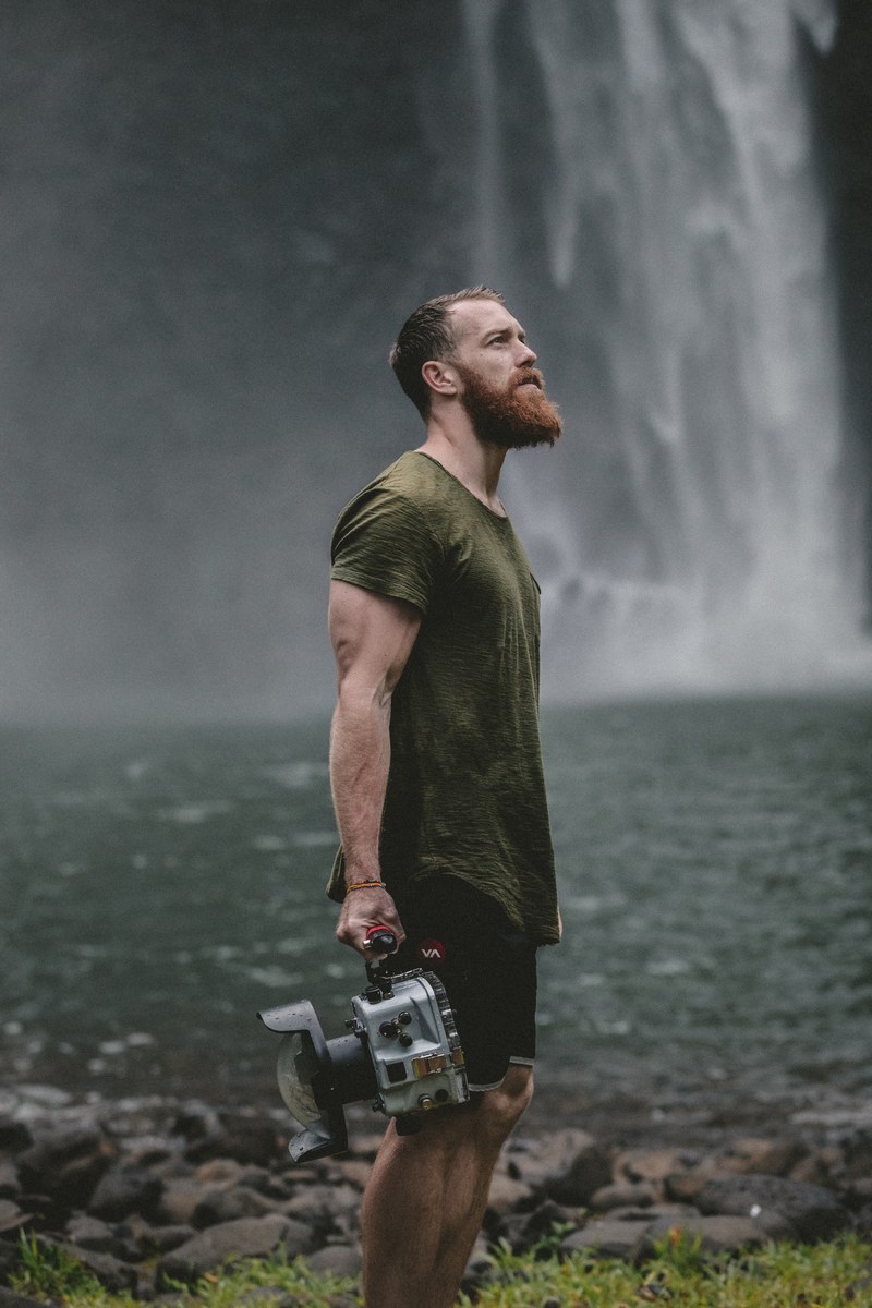 videographer carrying a camera near a waterfall, filming the wild 4k