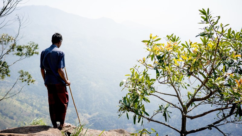 person stands alone on the edge of a cliff with a hiking stick, this man is called ab 4k