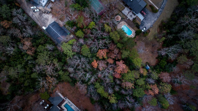 a drone shot of houses with pools at the edge of a forest in birmingham alabama, suburban houses near a forest 4k