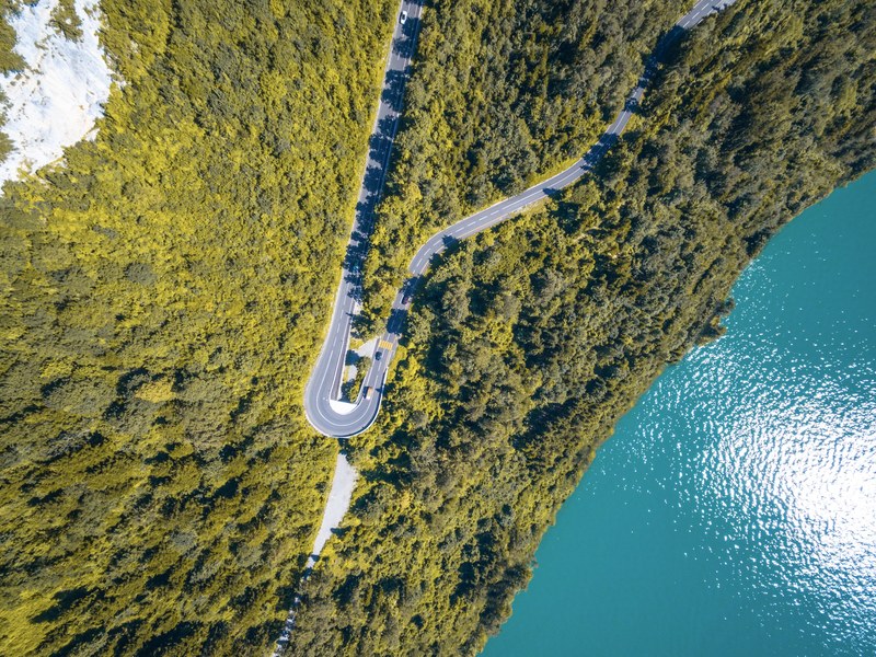 a drone shot of a sharp curve in a road along a shore of a lake in morschach, aerial view of a lakeside road 4k
