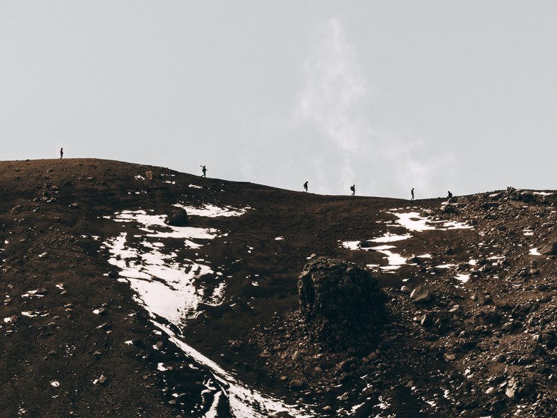group of hikers walking across a snow dusted ridge, ants on the hill 4k