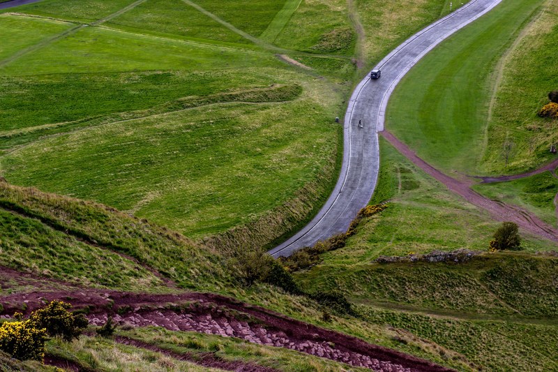 drone shot of car driving on countryside road surrounded by green fields in edinburgh scotland, car countryside road edinburgh 4k