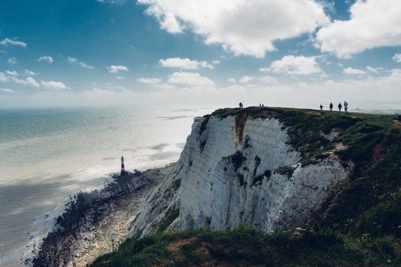 majestic white cliffs rise up from the sea with small human figures appearing on the crest, crest of white cliffs 4k