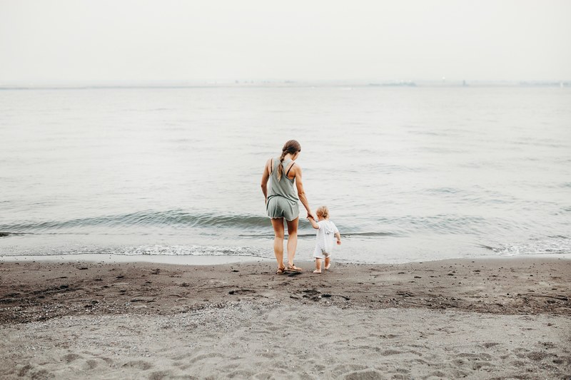 a mother and daughter walking down the beach near the water in wintler community park, motherhood 4k