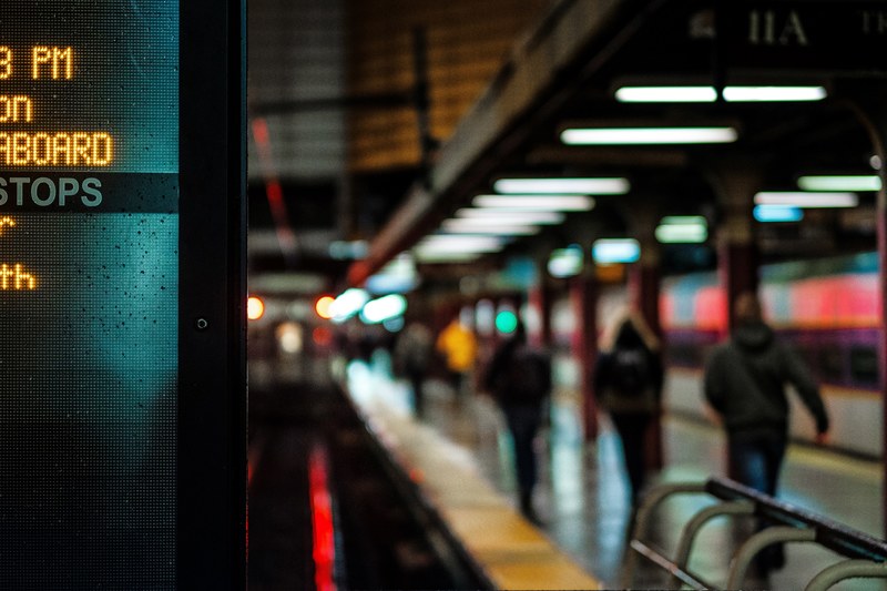 city subway platform lit with signs and commuters walking to their destination, urban public transportation 4k