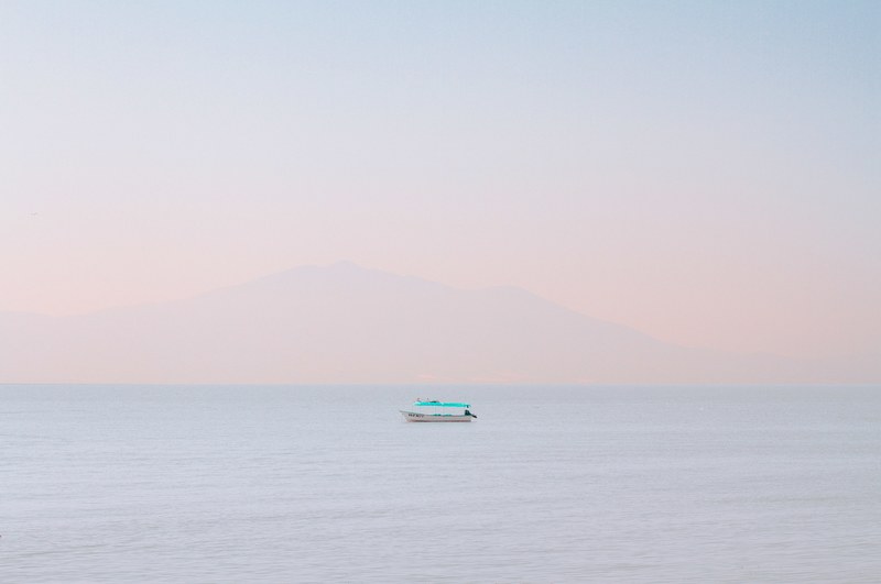 a single boat floating on the calm water during sunset or sunrise in chapala, pastel sky 4k