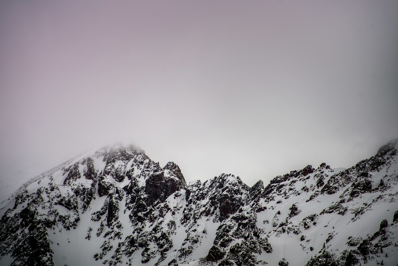 purple fog over snowcapped mountain peaks in red mountain, fog over jagged mountains 4k