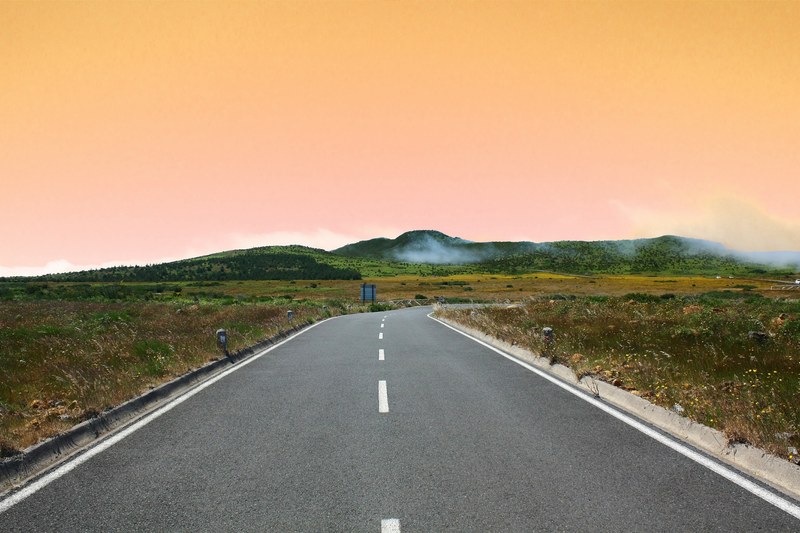 sunset drives through a countryside landscape, open road and orange sky 4k