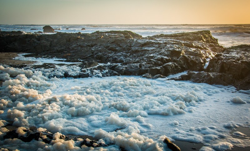 waves crashing and foaming up along the rocky coast of a sunset beach, waves on a rocky coast 4k