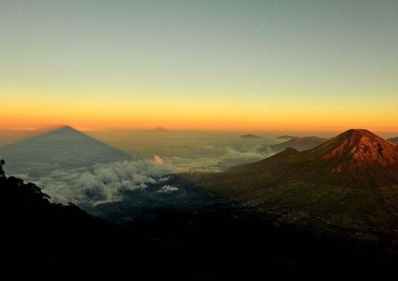 a volcano towering above a vast cloud covered plain during sunset, volcano at dusk 4k