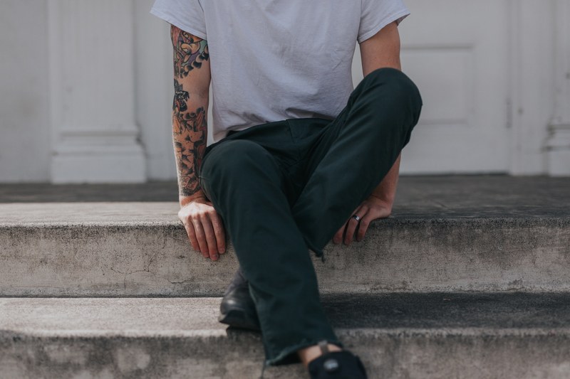 low shot of a person with an art tattoo sitting on a porch step, sitting on a porch 4k