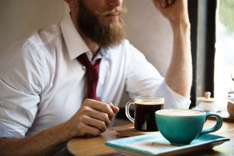 a bearded man in a shirt and a tie sitting at a table over a coffee, bearded man over coffee 4k