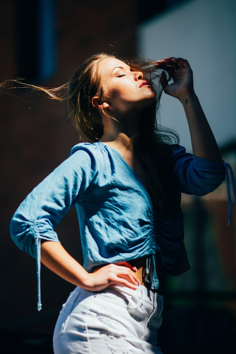 a woman closes her eyes and throws her head backwards raising her hand to her face, woman with head thrown back 4k