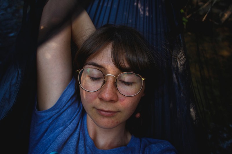 woman in retro circle glasses closing her eyes and relaxing, the most peaceful hammock 4k