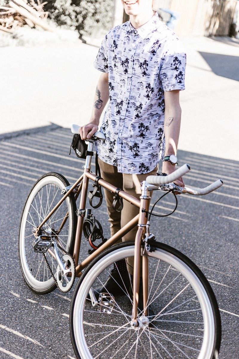 man wearing a watch and urban clothing holding a bicycle, bike ride 4k