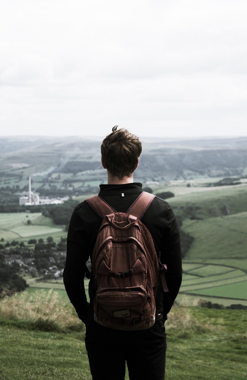 solo traveller stands in a backpack looking out at the rolling landscape, solo travel 4k