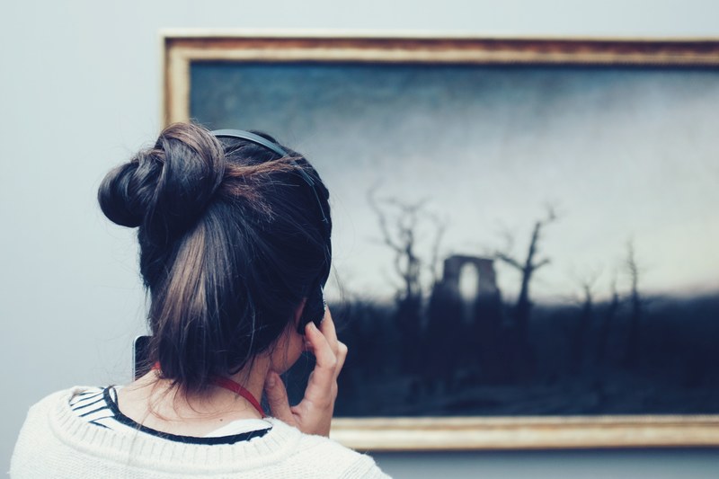 woman on a museum audio tour looking at a painting and listening through headphones, nationalgalerie i 4k