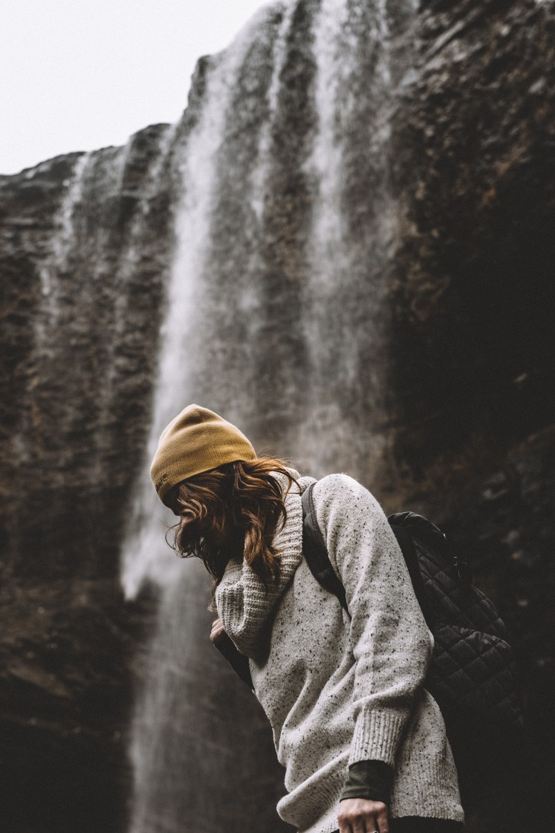 hiker wearing a backpack walking past a waterfall, waterfall hike 4k