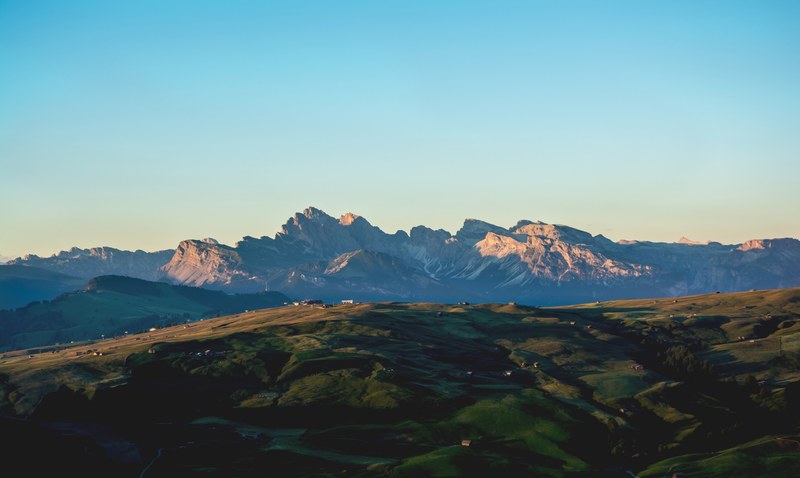 undulating countryside landscape with tall mountains at the back in schlern, countryside by the mountains in schlern 4k