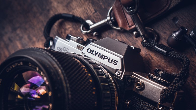 olympus cm10 camera with a black wool strap headphones and a leather key holder, creativity 4k