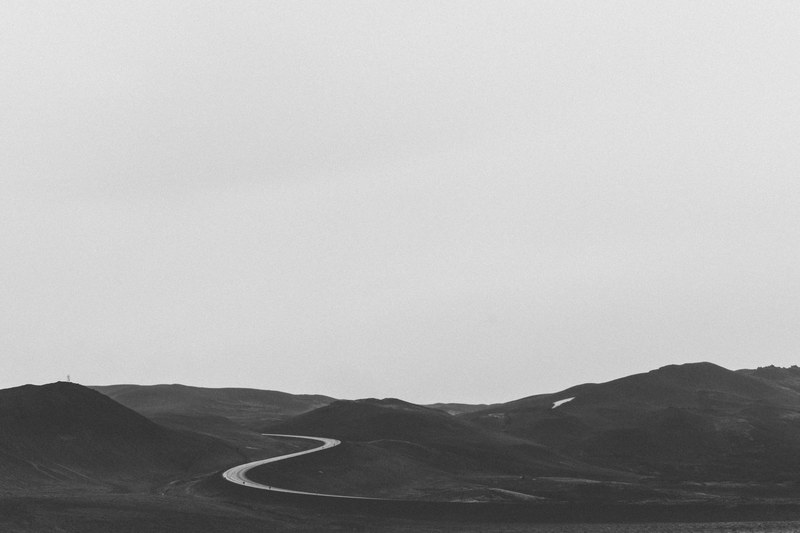 black and white long shot of winding road through hills and sky, monochrome road in hills 4k