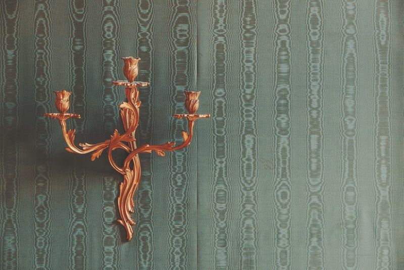 an ornamental brass candleholder on a wall, floral candleholder 4k