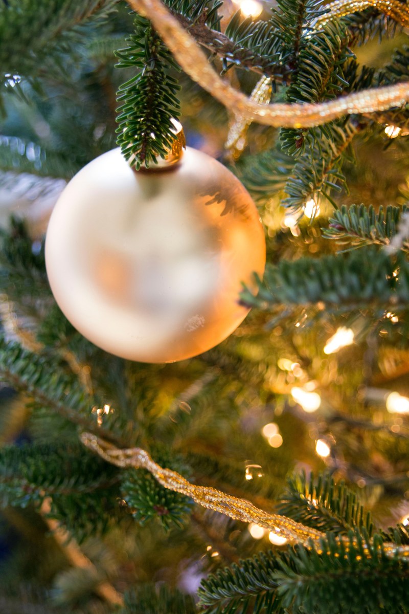 a white christmas ornament hanging from a lit xmas tree, _white xmas ornament 4k