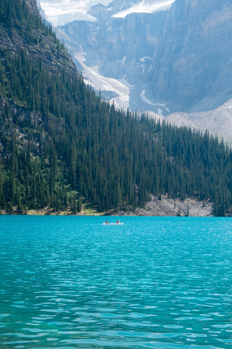 broad landscape capturing the forest around the lake louise with people in a canoe, lake louise in summer 4k